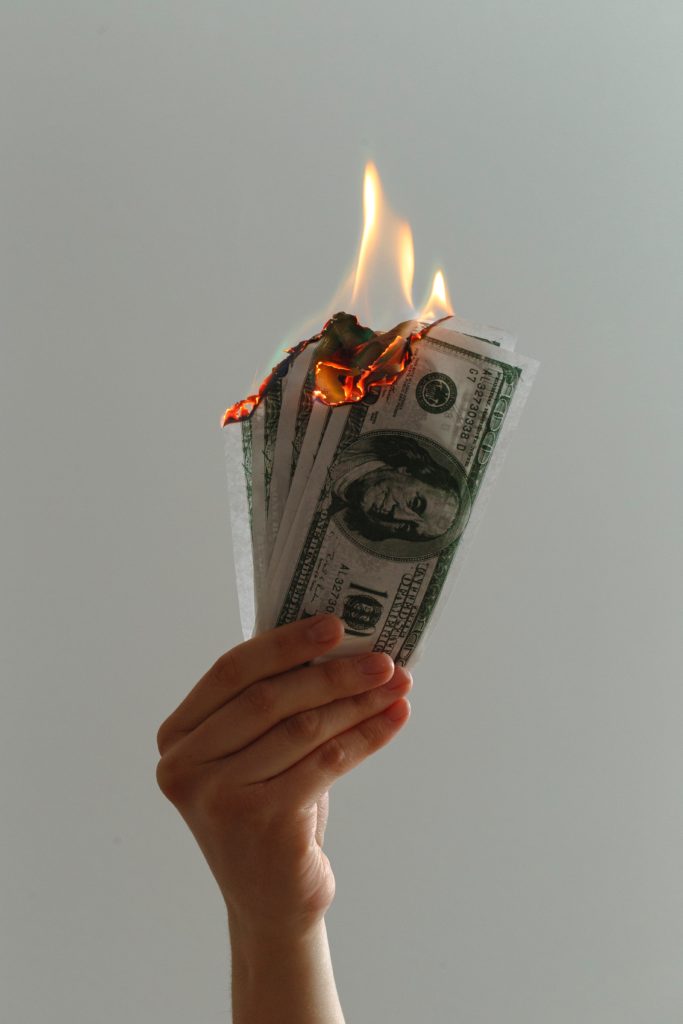 Person holding money on fire.